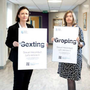Clare McNaught and Jackie Andrews holding campaign posters showing the word "Sexting" and "Groping" cut through the middle with a scalpel